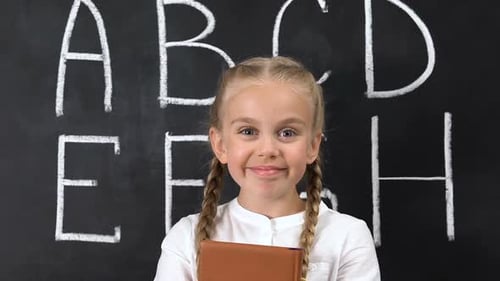 Smiling Girl with Book in Front of Chalkboard