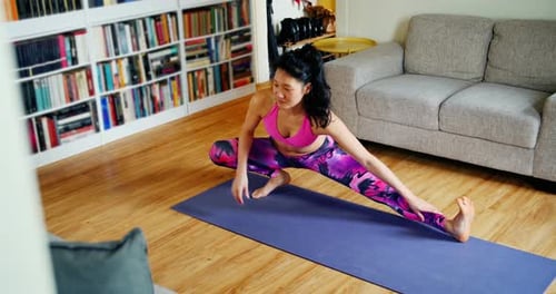 Woman Stretching on Yoga Mat in Home