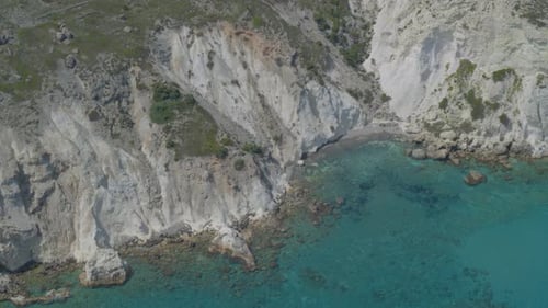Aerial Pan of Cliffs Cascading into the Beautiful Blue Aegean Sea in Milos