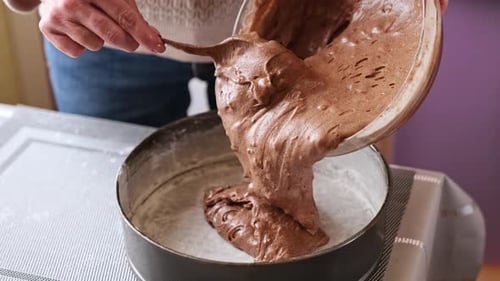 Femme met la pâte au chocolat avec la pâte aux noix dans un plat allant au four
