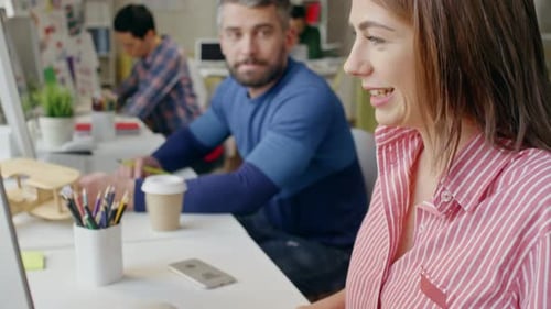 Femme discutant avec un collègue tout en travaillant