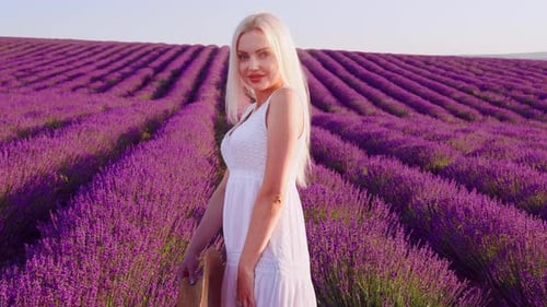 Portrait d'une femme blonde avec un chapeau dans les champs de lavande en été