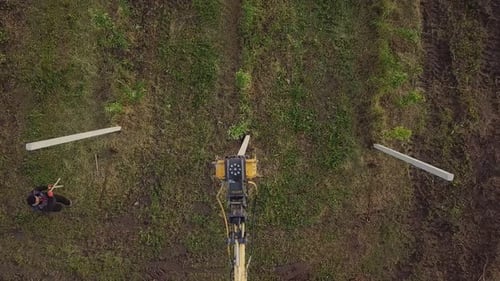 Excavator Places Wooden Posts in Rural Field