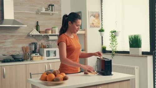Woman Toasts Bread in a Bright Kitchen