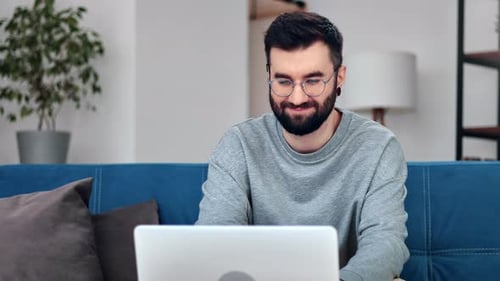 Man Working on Laptop on Couch Indoors