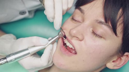 Young woman receives professional teeth cleaning in cosmetic dentistry clinic