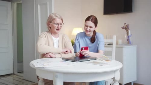 Senior Woman Learning Technology from Young Adult