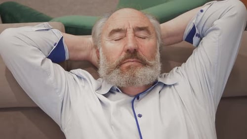 Man Resting on Couch with Hands Behind Head