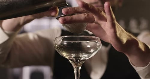 Bartender Pouring Red Cocktail Through Strainer Into Glass
