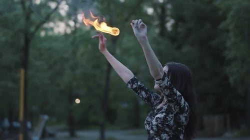 Grace Beautiful Girl Performing a Show with Flame Standing in Front of Forest