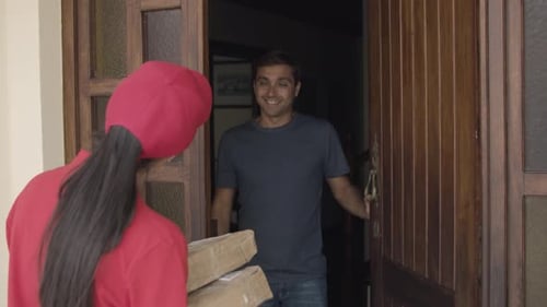 Woman Delivers Packages to Smiling Man at Door