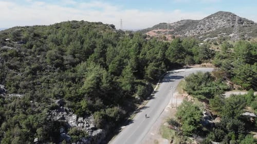 Cyclist Rides Mountain Road Through Verdant Hills