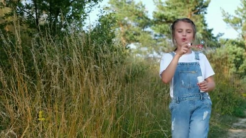 Little Baby Girl Blowing Soap Bubbles While Walking in the Park