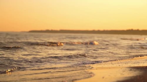 Abends spritzt Meerwasser am Sandstrand. Der Rand des Ozeans mit ruhigen Wellen