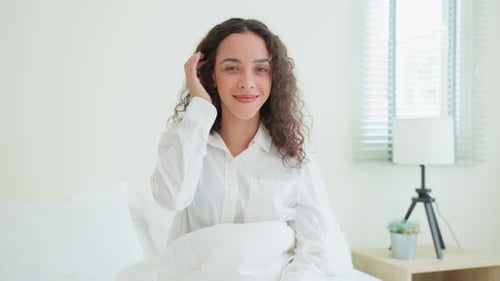 Smiling Woman with Curly Hair in Bed