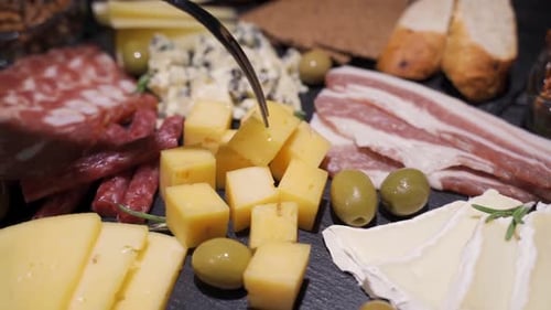 Diapositive au Ralenti d'une femme prenant des morceaux de fromage sur une planche à olives