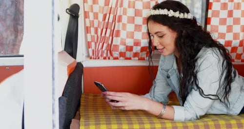 Woman Lies in Camper Van Using Mobile Phone