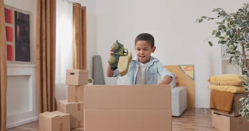 A Cute Little Boy Unpacks His Toy Box After Moving to a New House Pulls Out a Car Enjoys It Plays