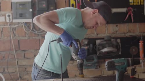 Man Drilling Into Wood In Bright Workshop