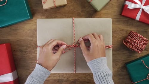 Woman hands tying bow with string on top of Christmas gift box