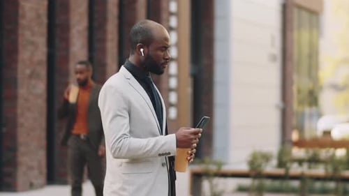 African American Businessman Standing with Smartphone and Coffee on Street