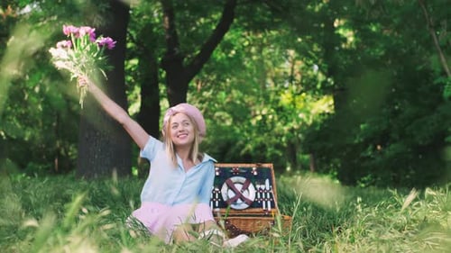 Happy Smiling Young Woman Having Fun with a Bouquet of Flowers Outdoors in Park on Picnic