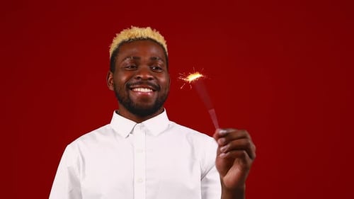 African American Man Holding a Burning Stick of Dynamite in Studio Red Background