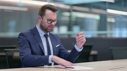 Stressed Businessman with Documents in Modern Office