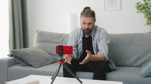 Young Adult Streaming Video on Smartphone at Home