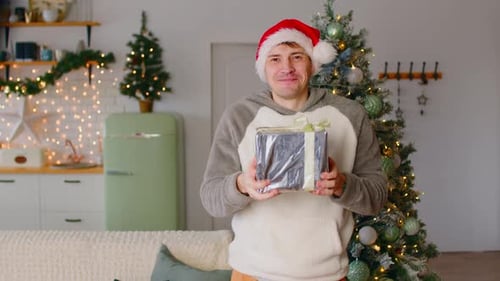 Man in Santa Hat Holding Christmas Gift