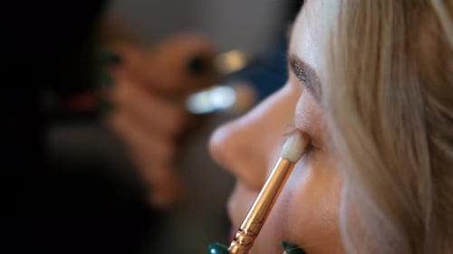 Maskenbildner induziert Wimpern mit einem Pinsel/Mascara