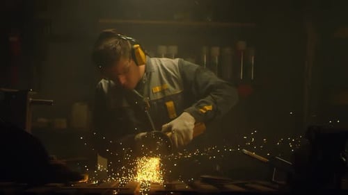 Worker Sparks Flying With Grinder in Dark Workshop