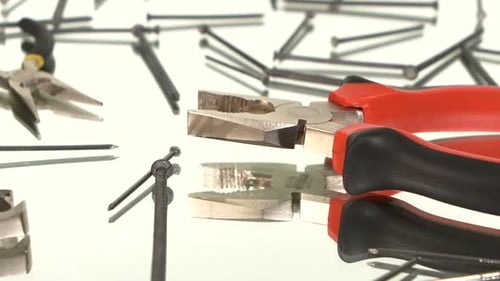 Shiny Nails and Pliers on White Reflective Surface