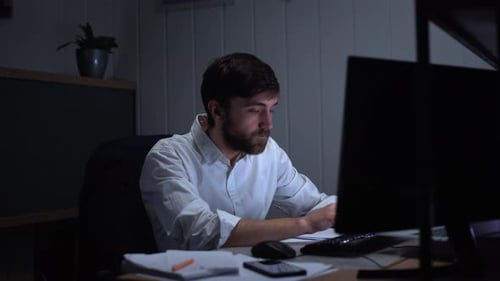 Portrait of Concentrated Young Man 20s in White Shirt Looking Depressed and Worried While Working in