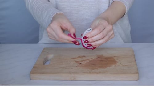 Woman Removes Peel From Slice of Dragon Fruit