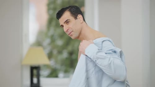 Handsome Man Putting on Blue Shirt Indoors
