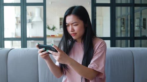 Woman playing game on smartphone at home