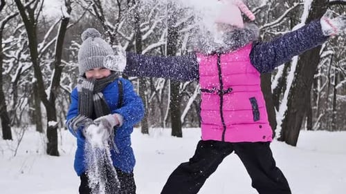 Junge und Mädchen laufen im Schnee in einem Winterwald und werfen Schnee auf ihren Kopf