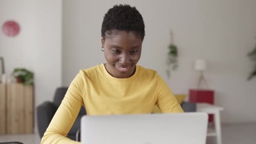 Woman Smiling While Using Laptop at Desk