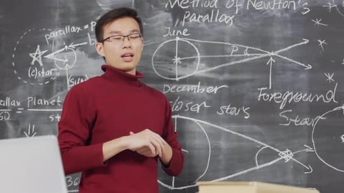 Asian Physicist Presenting New Project at Chalkboard