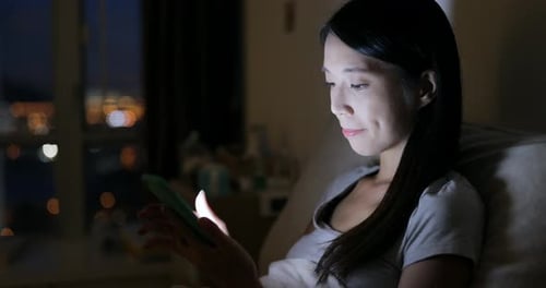 Young Woman Uses Smartphone at Night