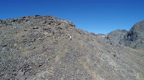 Mountain Hiker Scaling Rocky Peak on Sunny Day