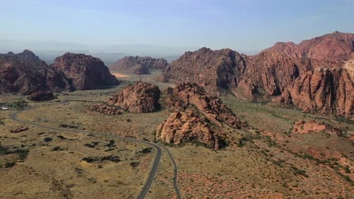 Aerial View Of Remote Road Amidst Towering Sandstone Mountains In Utah Deserts.