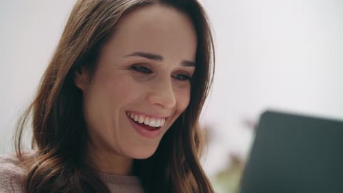 Woman Smiling and Laughing While Looking at Laptop