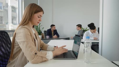 Empresaria que usa una computadora portátil en una oficina de espacio abierto