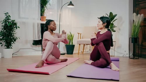 Two Women Practicing Yoga in Bright Home Studio