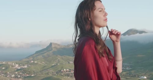 Side View of a Woman Walking Along the Top of a Hill in the Rays of the Sunset Against the