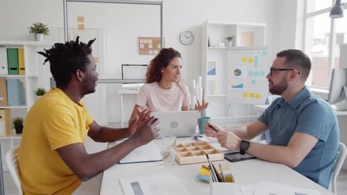 Three Multiethnic Coworkers Talking Joyfully in Office