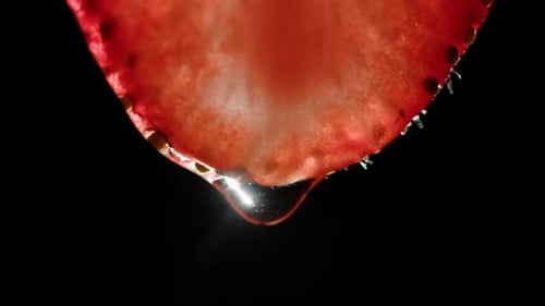 Strawberry Slice with a Glistening Droplet on Black