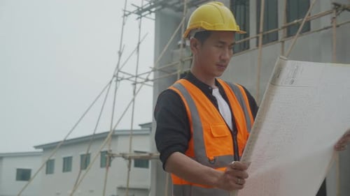 Engineer Reviews Building Plans on Construction Site